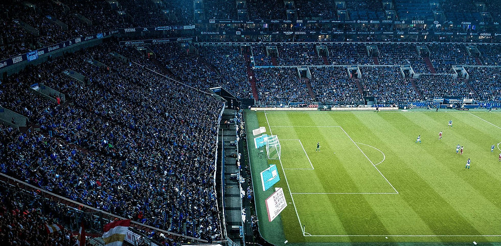 A packed stadium roars with excitement as fans watch an intense soccer match unfold on the vibrant green pitch.