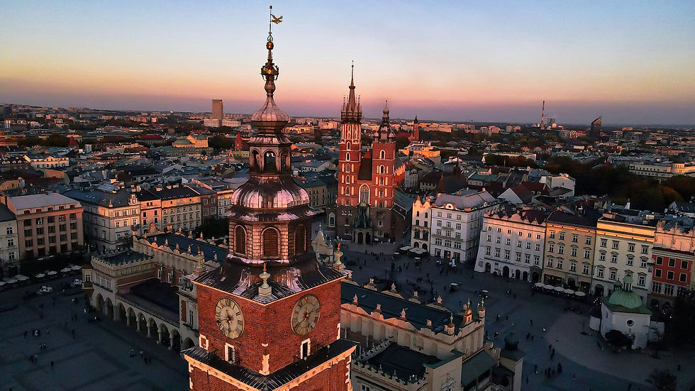 A breathtaking aerial view of Kraków at sunset, showcasing the majestic architecture of the historic city, with the clock tower and St. Mary's Basilica standing prominently in the vibrant cityscape.