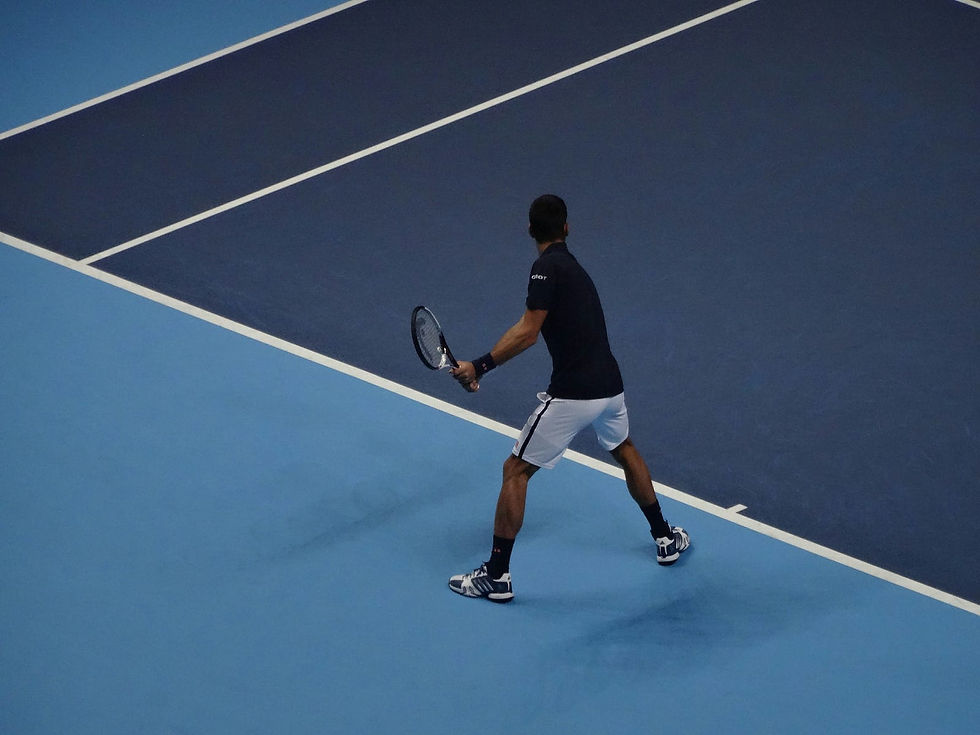 A tennis player prepares for a serve on an indoor hard court, focused and ready for action.