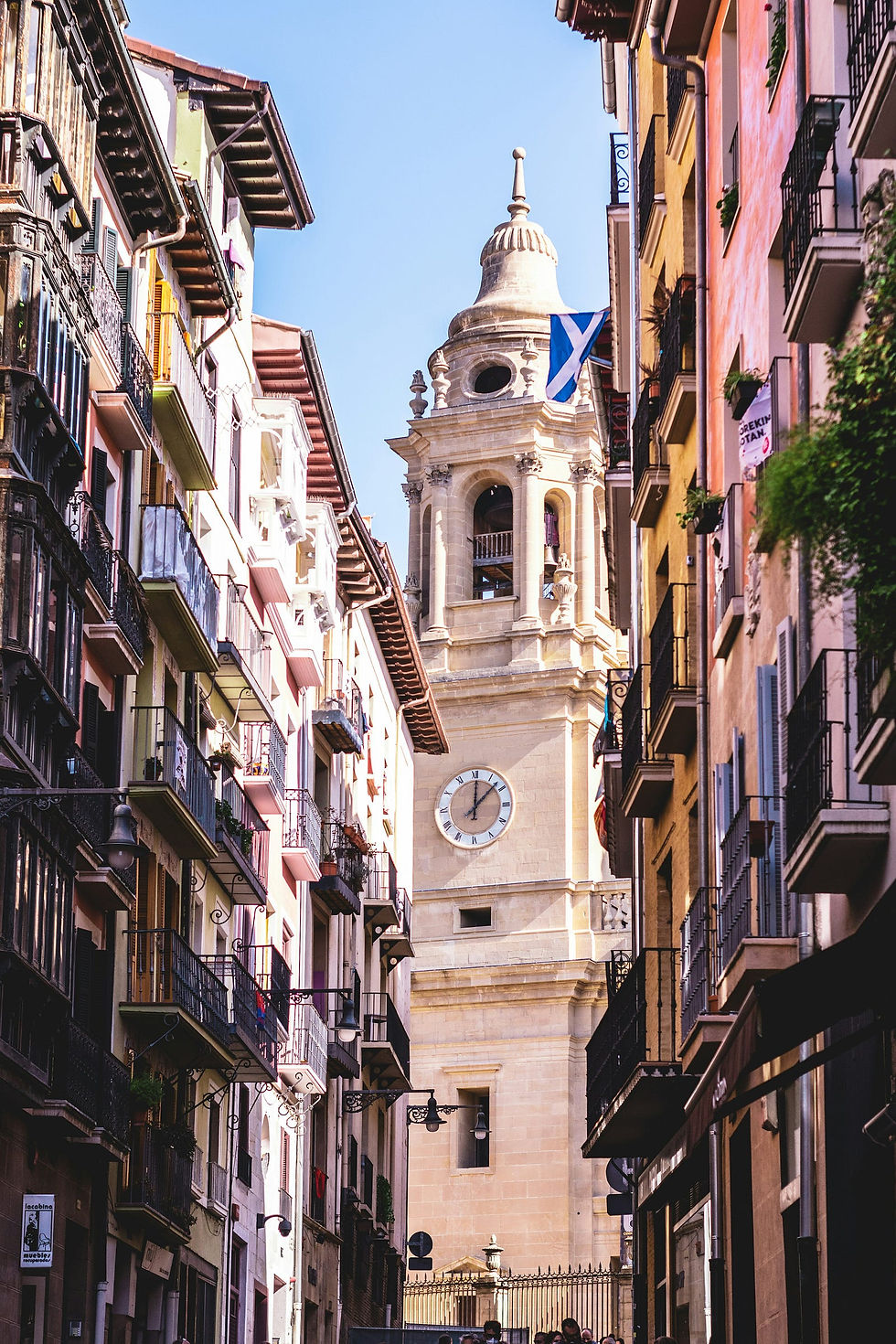 Street view in Pamplona showcasing the elegant architecture of the town hall with its detailed clock tower framed by colorful, charming buildings.