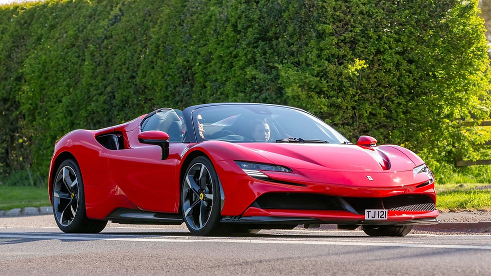 A sleek red convertible sports car cruises along a sunlit road, showcasing its aerodynamic design against a lush green backdrop.