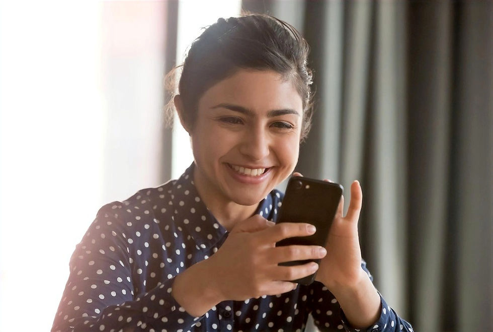 A young woman smiling while looking at her phone