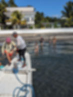 people in water walking toward boat