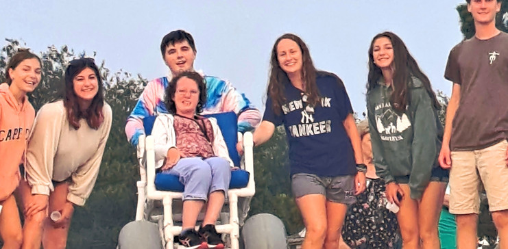 A group of retreatants on the beach with a girl in a wheelchair