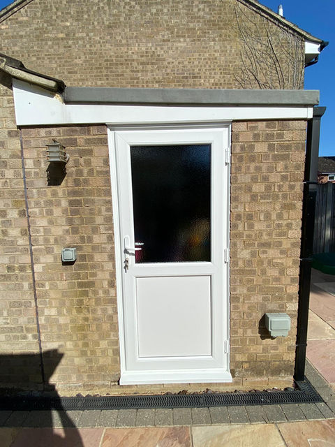 White PVC-U back door with large central glazed panel on a buff brick extension.