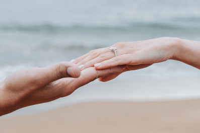 a mans hand is extended out holding a womans hand. there is a ring on her left finger.