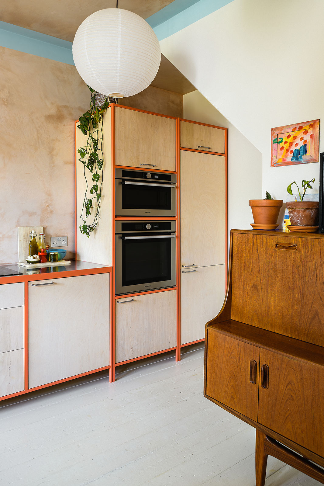 Industrial-style kitchen in a Victorian terrace with RAL 3022 steel frames, birch plywood units, stainless steel worktop, vintage G-Plan dresser, and French doors for added light.
