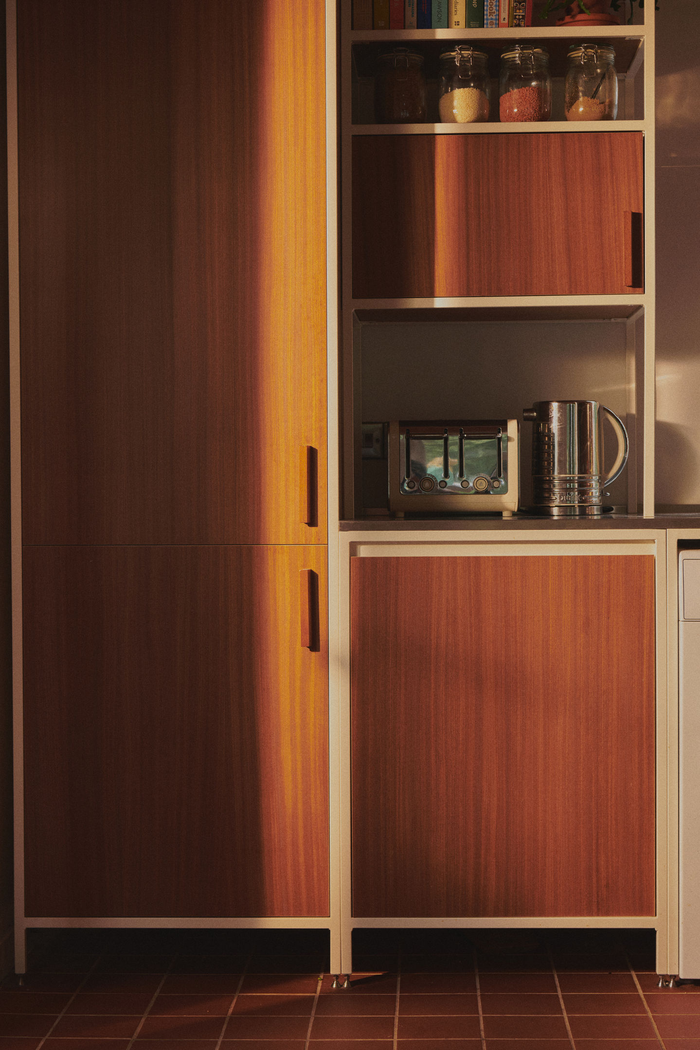 Mid-century kitchen with RAL 9010 steel frames, Sapele veneer, reeded glass wall units, stainless steel worktop, teak ceiling panels, and vintage-style tiles.