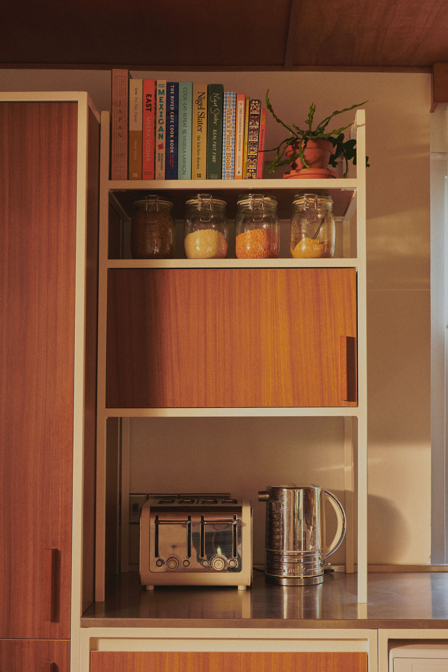 Mid-century kitchen with RAL 9010 steel frames, Sapele veneer, reeded glass wall units, stainless steel worktop, teak ceiling panels, and vintage-style tiles.