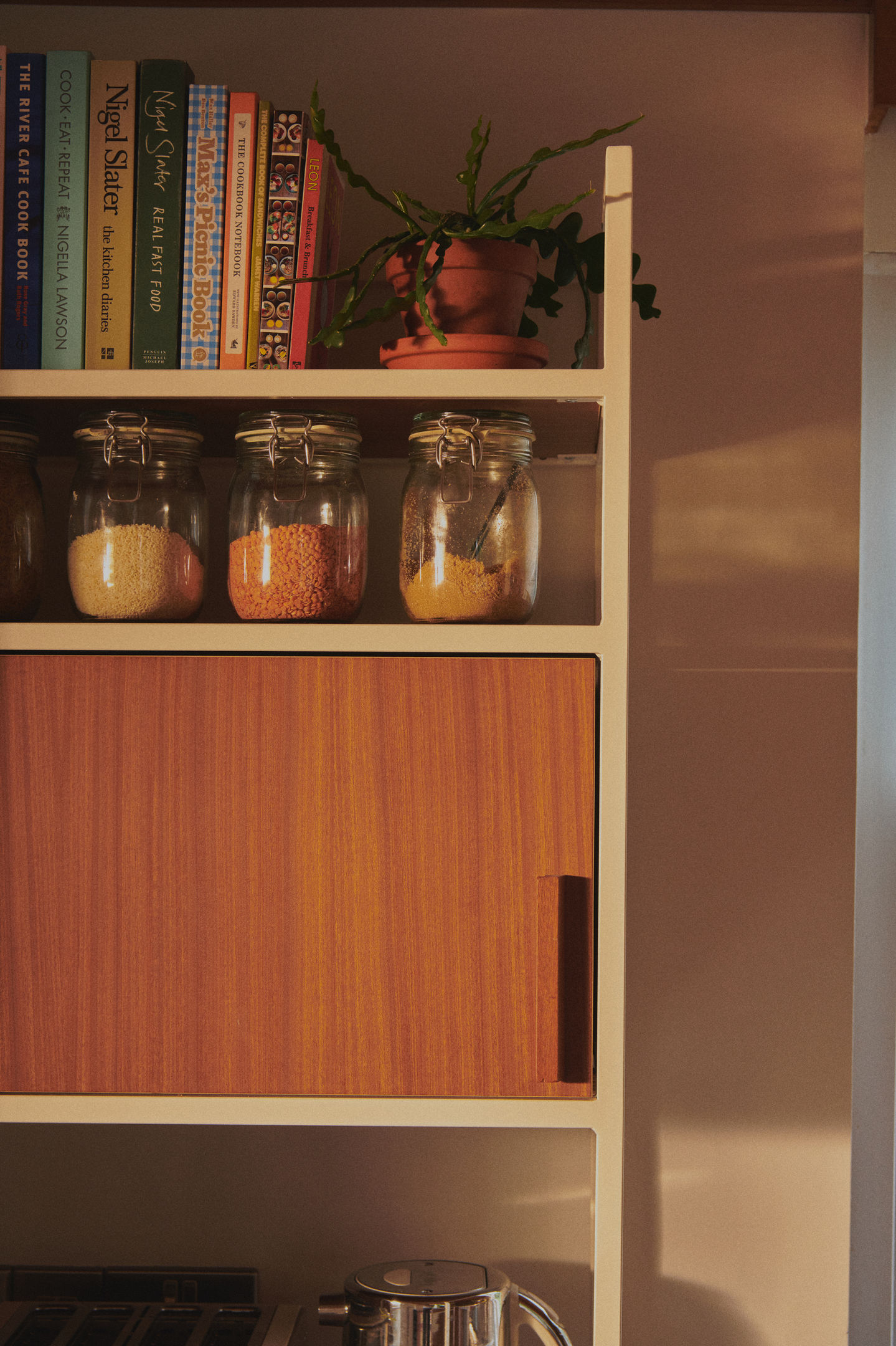 Mid-century kitchen with RAL 9010 steel frames, Sapele veneer, reeded glass wall units, stainless steel worktop, teak ceiling panels, and vintage-style tiles.