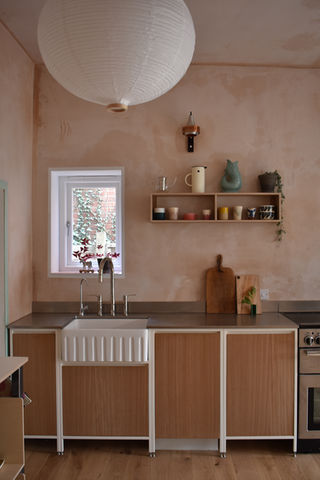 Clean and elegant, refined and minimalist, white cabinet edges, crisp white structure, rich wood veneer, dark timber cabinetry, 	natural wood hues, golden brown tones, raw plaster texture, natural wall finish, 	industrial-style surface, metal countertop, ribbed farmhouse sink, textured ceramic basin, 	classic kitchen taps, vintage-style mixer, extended base cabinets, continuous lower storage.