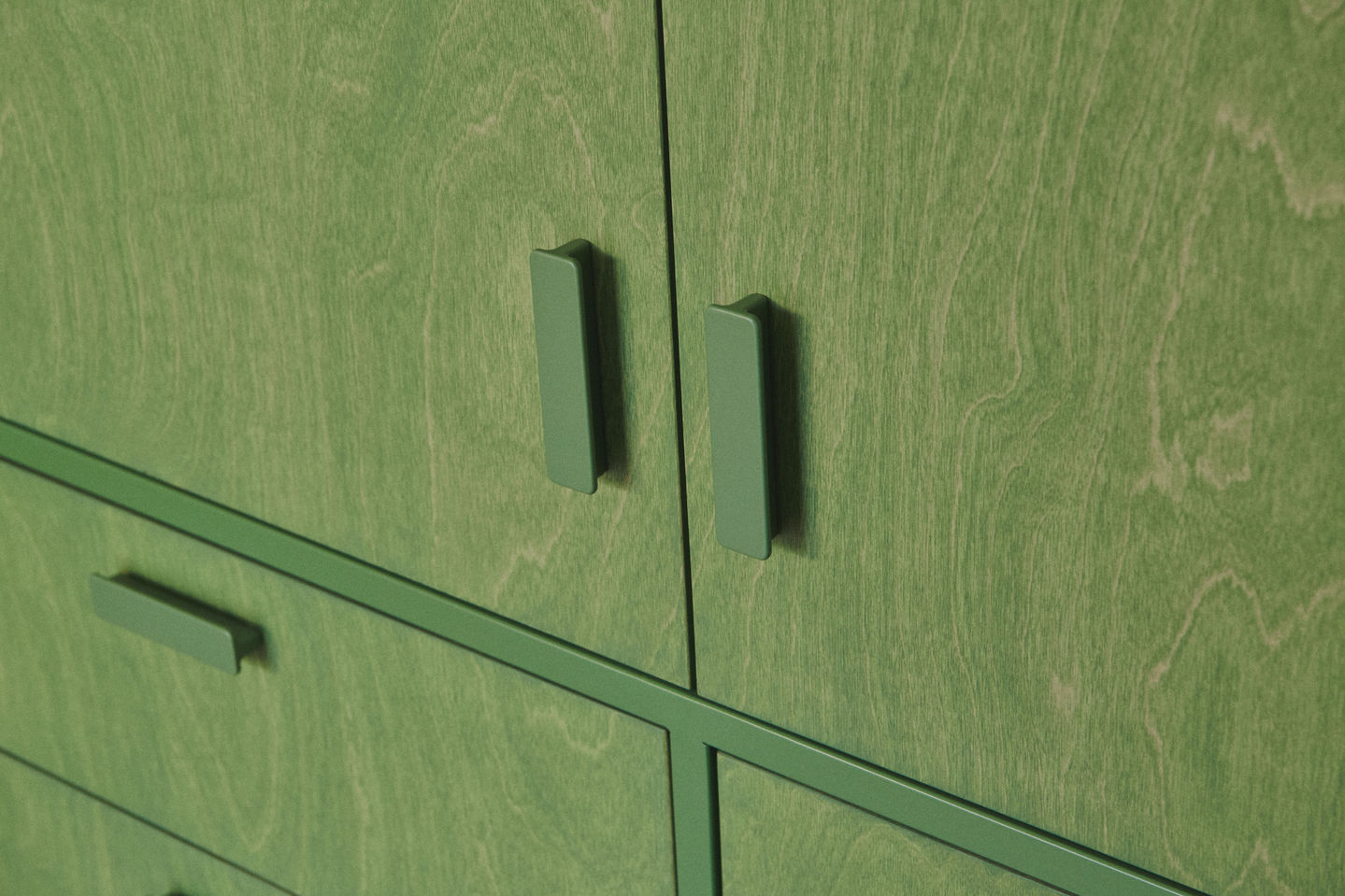 Sage green galley kitchen with RAL 6011 steel frames, stained birch plywood fronts, raw white quartz worktop, open shelving, and quarry tile floor.