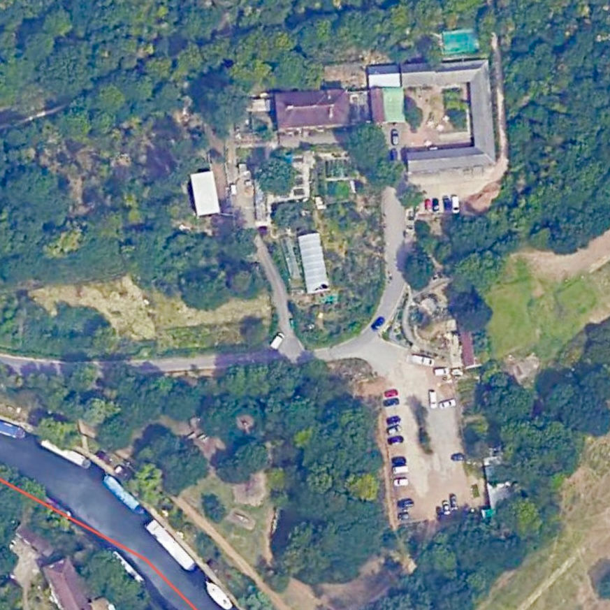 An arial photograph of a farm and surrounding woodland, with a road leading up to a car park by the farm. A canal can be seen to the bottom left of the picture.