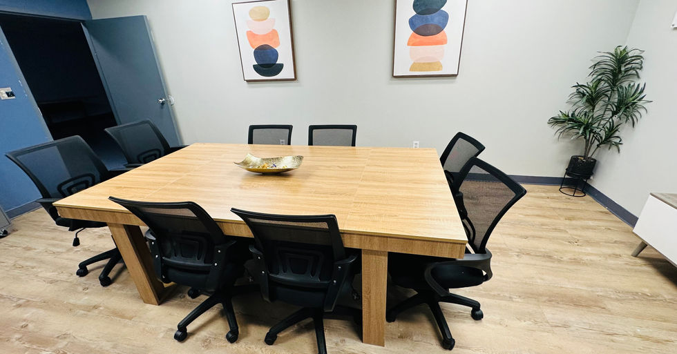 Another view of the New Birth Christian Ministries and Cancer Ministries conference room with long table, office chairs, and artwork on the wall