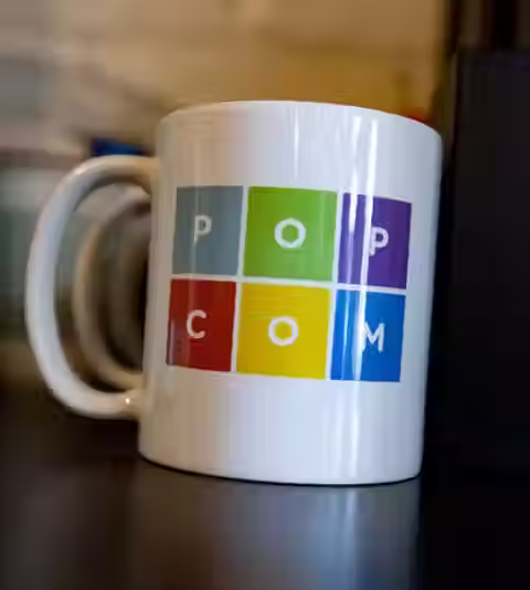 A closeup of a mug with the Popcom LLC logo on it