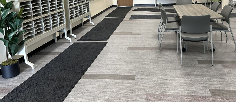 A gathering space with a long table and 4 grey chairs, and a storage unit with mail slots across from the table.