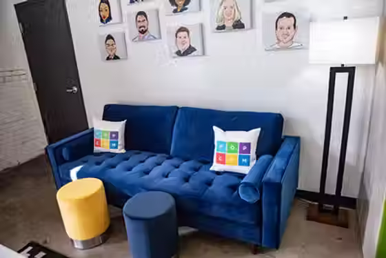 A plush blue couch with pillows and footstools
