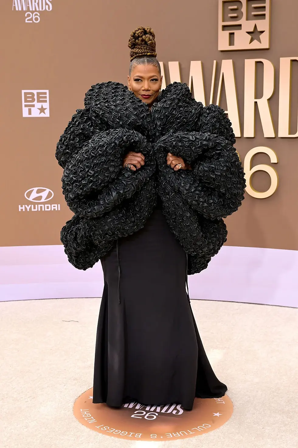 Queen Latifah attends the 2026 BET Awards wearing a sculptural black designer ensemble with dramatic volume.