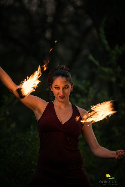 A woman in a red dress dancing with fire poi