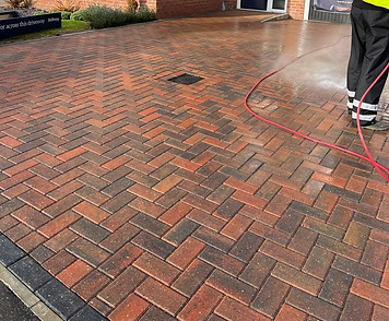 a block paved driveway being cleaned with a power washer