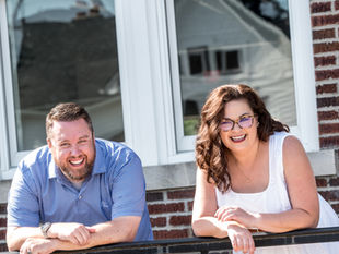 male and female on a sunny day standing in front of a brick building 