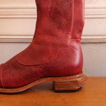 Custom and handmade tall knee boots in red distressed/antiqued leather featuring a hand carved stacked asymmetrical angular heel, made by bespoke and orthopedic shoemaker Daphne Board in western Massachusetts, USA