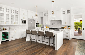 A modern, elegant kitchen featuring white kitchen cabinets and countertops, accented with striking gold handles, showcasing a clean and sophisticated design.