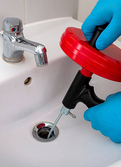 royalty plumbing tech working on a clogged sink