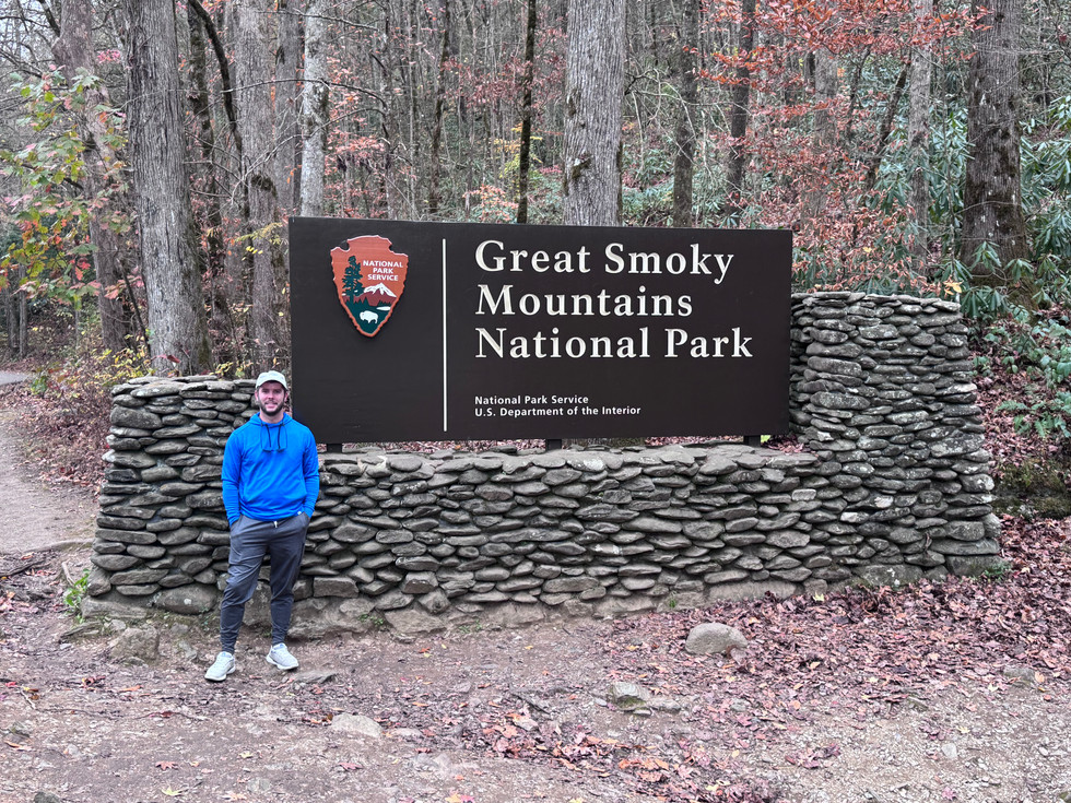 A man standing in front of the Great Smoky Mountains national park entrance sign