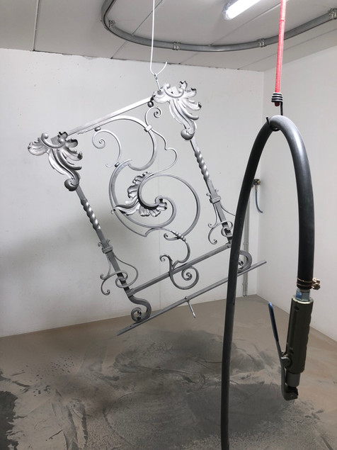 Tuyau de sablage suspendu devant grille de fer forgé