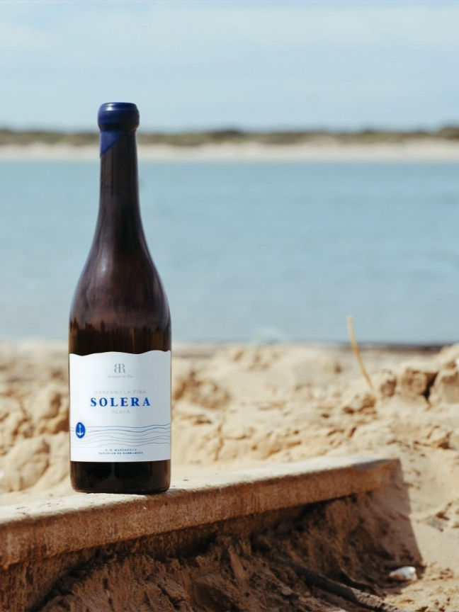 A Bodegas del Río Solera Playa Azul bottle, with a body of water behind it.