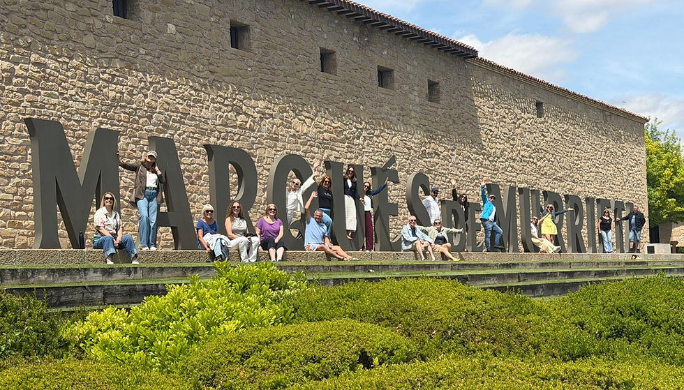 Our wine weekenders sitting or standing in front of the Marques de Murrieta signage at the bodega.