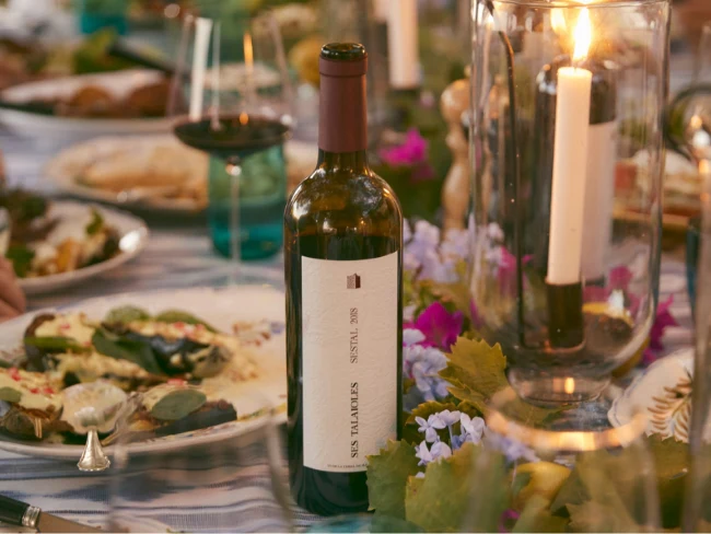 Una botella de Ses Talaioles Sestal abierta en una mesa durante una cena.
