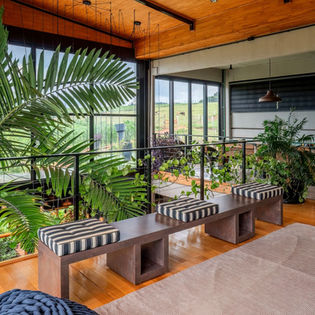 Pavimento superior da casa de campo que une arquitetura em madeira e arquitetura industrial, piso em assoalho de madeira mesclado com piso de cimento queimado, peitoril em cabos de aço, parede em painel de concreto aparente, sala de estar e sala de jogos, assinatura Arquiteta Isabella Dalfovo.