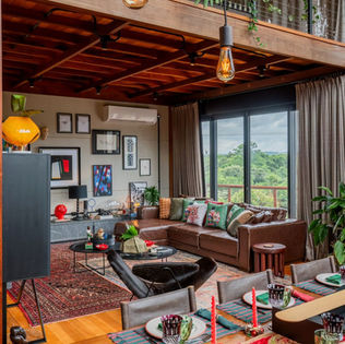 Living de TV de casa de campo com arquitetura contemporânea: forro em madeira que é o piso do mezanino, assoalho de madeira, móveis em couro e painel de concreto aparente — sofisticação e mistura de estilos