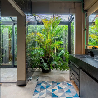 Banheiro estilo loft de Nova York: concreto aparente no piso e paredes, móveis em tons de grafite, grandes panos de vidro integrando o jardim externo e cobertura em vidro — sofisticação e contemporaneidade