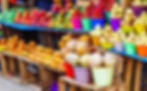 Vibrant market stall with assorted tropical fruits in colorful buckets. Background of wooden crates and blue tarp creates a lively, cheerful mood.