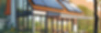 Modern house with solar panels on a gabled roof, surrounded by lush greenery. Large glass windows and a patio create an eco-friendly vibe. The image represents Net-Zero Home Construction for Contractors.