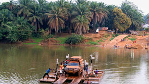 Een Land Cruiser steekt de rivier over op een ferry. Op de achtergrond aardewegen en jungle