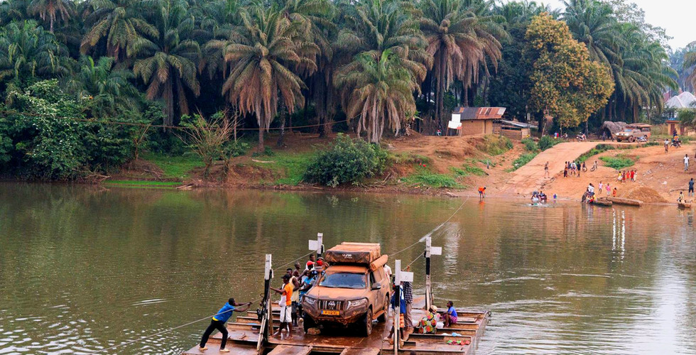 De Land Cruiser steekt de rivier over in de jungle op een ferry die door mannen getrokken wordt.