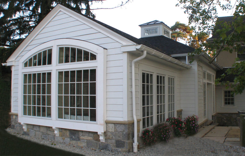 A White House with a large window, vinyl siding, and stone work.