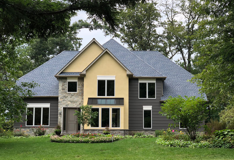 A home with cool-toned siding and yellow stucco. 