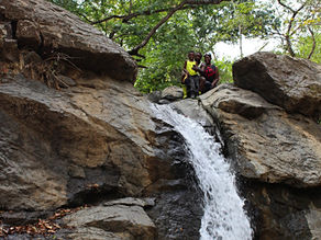 Family of three standing at the top of a waterfall in Sardinal, Costa Rica, enjoying the view and adventure