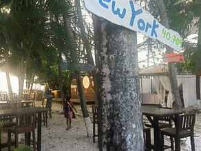 Wooden signpost in Costa Rica showing the distance in miles to New York.