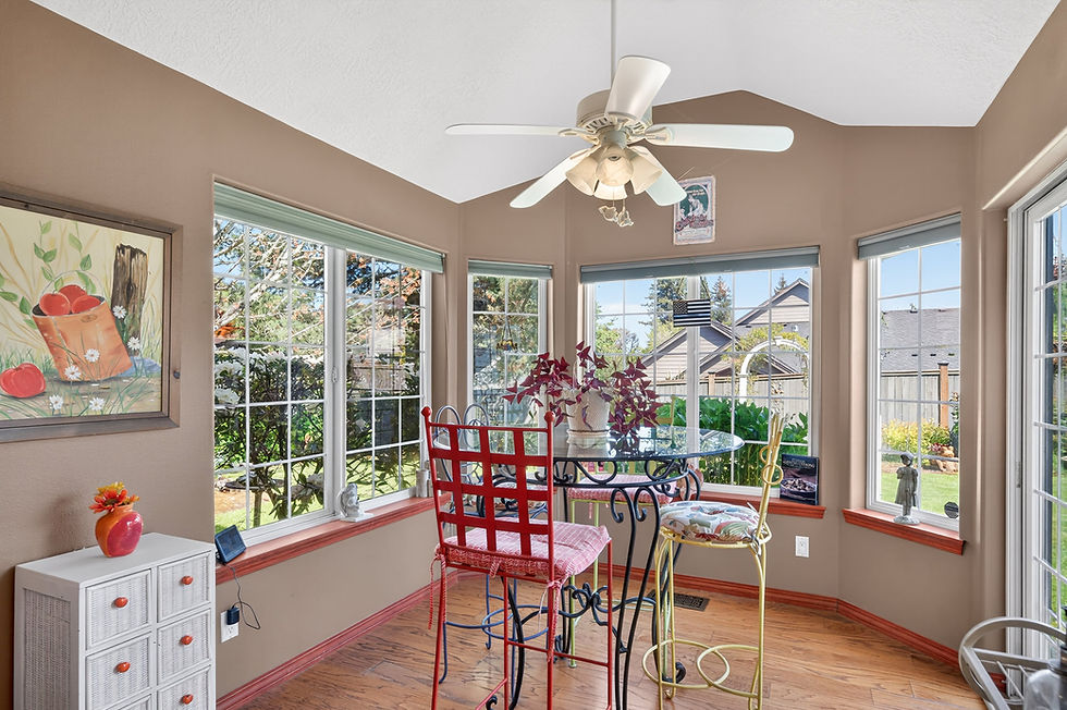 Sunlit room with large windows, a red and yellow chair around a glass table with a plant. Bright and cozy.