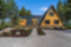 A-frame home with a black metal roof and tongue-and-groove cedar siding, complemented by clean landscaping and a gravel driveway.