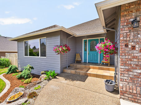 The front porch of 671 NW Allen Court with a turquoise front door and hanging baskets.