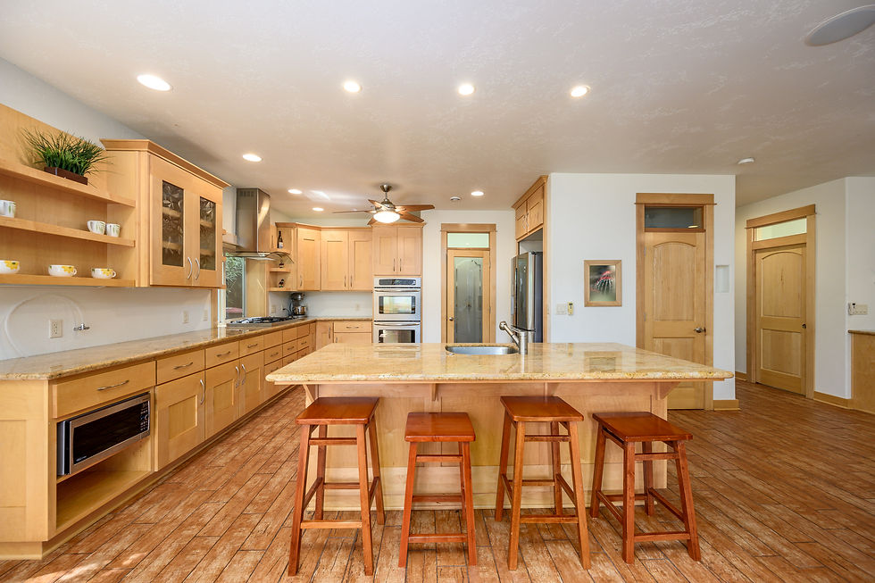 Spacious kitchen with wooden cabinets, island, and bar stools. Bright lighting, and stainless appliances.
