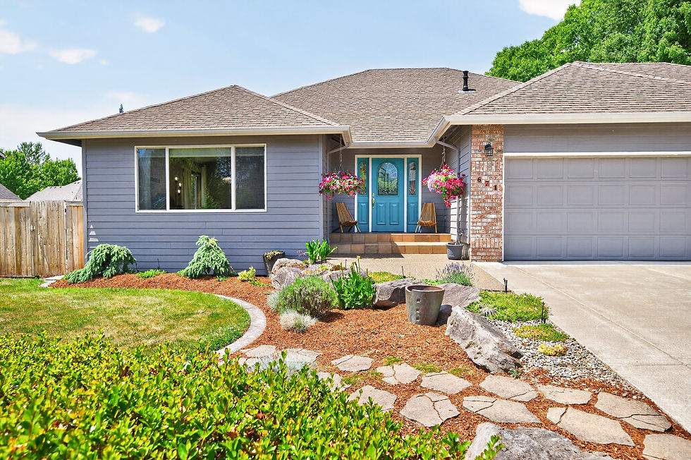 Sunny suburban house with blue front door, flower baskets, gray garage, and landscaped yard under a clear sky.