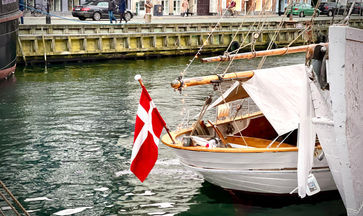 A boat with a flag from Denmark stationed at Nyhavn harbor in Copenhagen